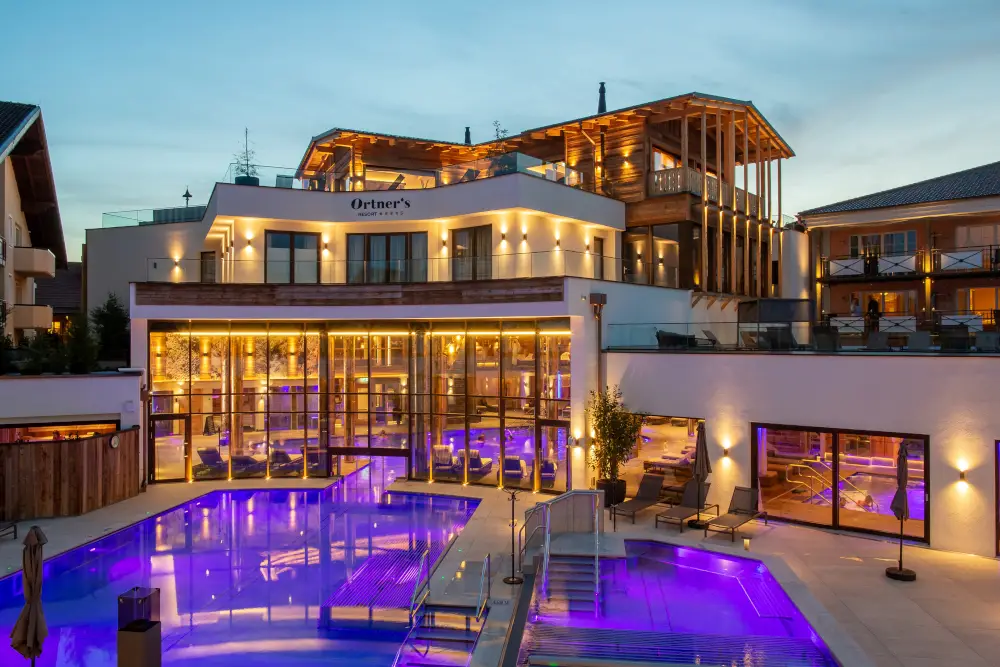 Luxurious spa resort at dusk with illuminated pool and elegant architecture.