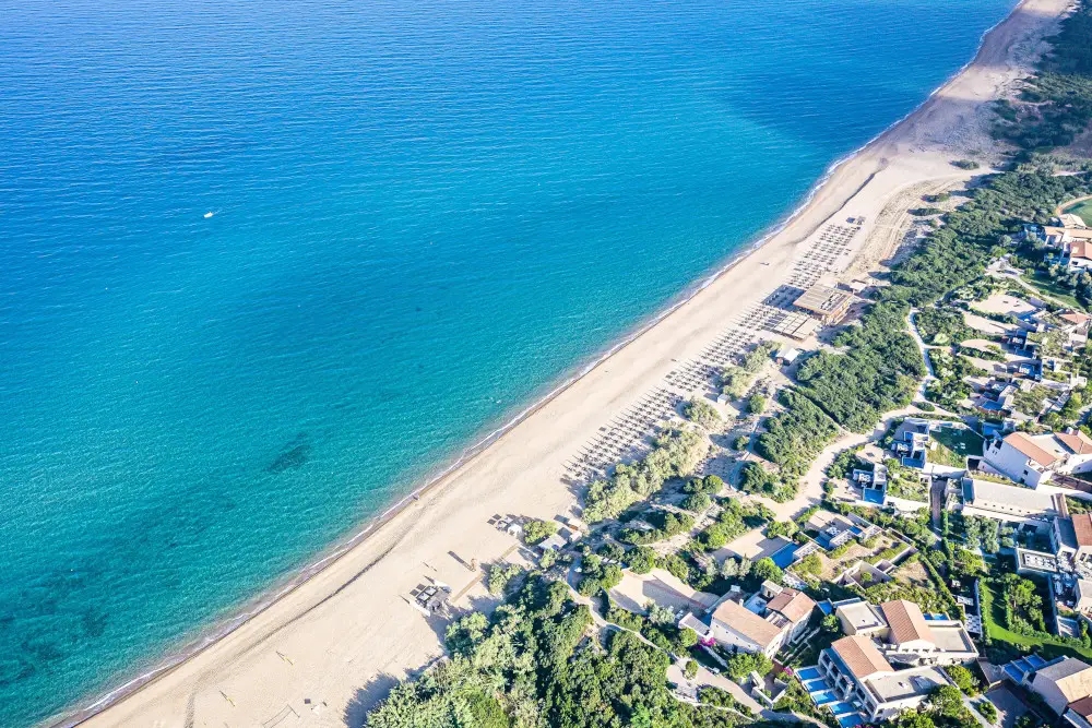 Aerial view of luxurious beachfront spa resort with pristine blue waters.