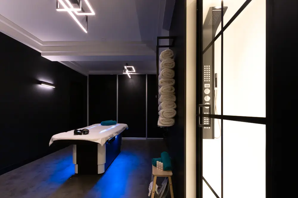 Luxurious spa room with Gharieni treatment table, ambient lighting, and neatly stacked towels.
