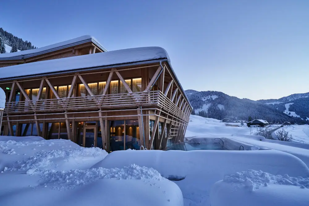 Modern spa retreat with snow-covered wooden architecture in a serene mountain setting.