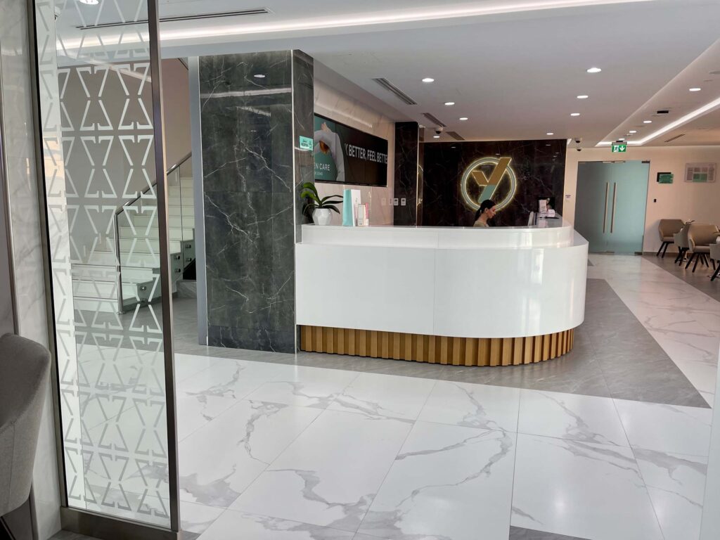 Modern spa reception with sleek white counter, marble accents, and elegant lighting.
