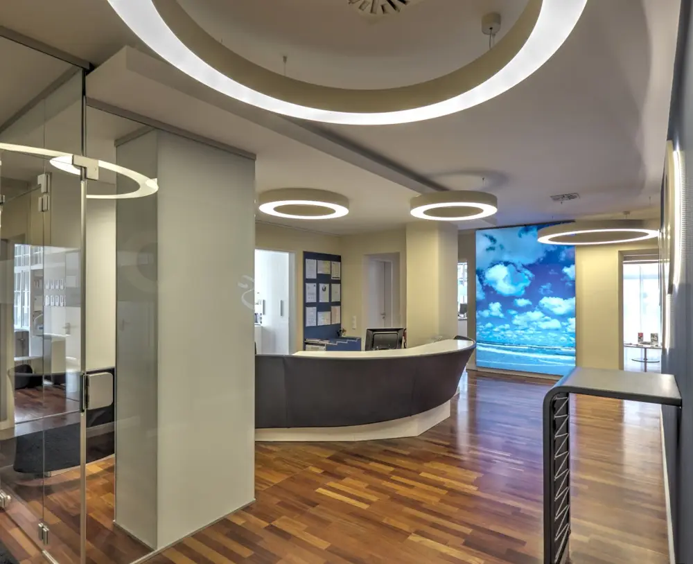 Modern spa reception with sleek design, featuring circular lighting and ocean-themed wall art.