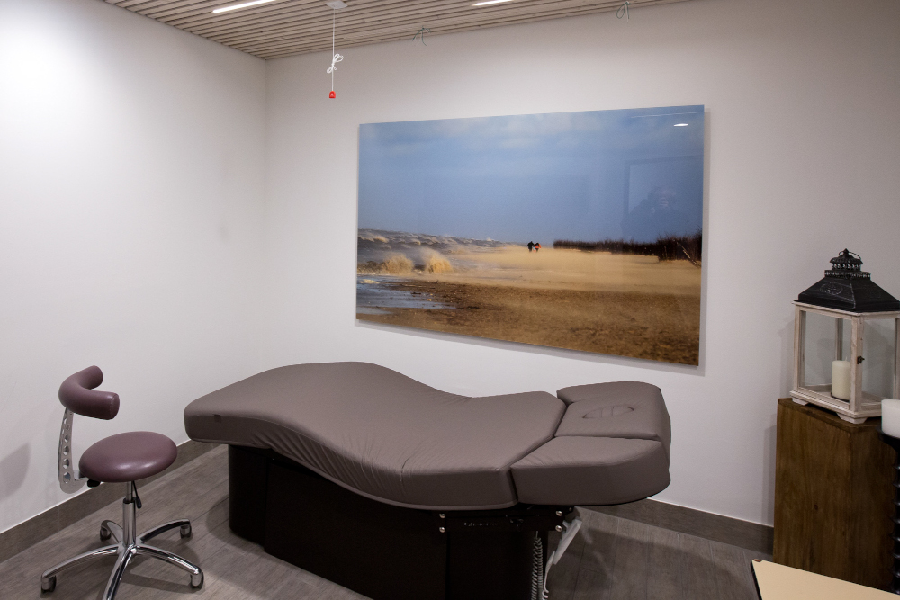Luxurious spa treatment room with ergonomic massage table and serene beach artwork.