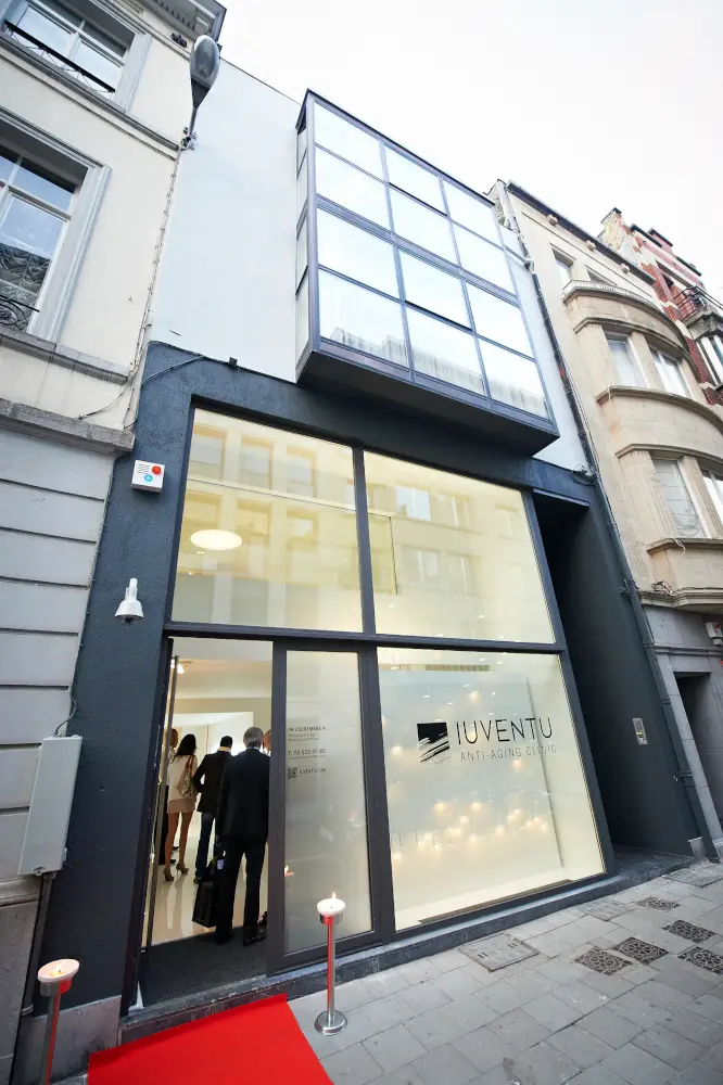 Modern spa center facade with large glass windows and red carpet entrance.