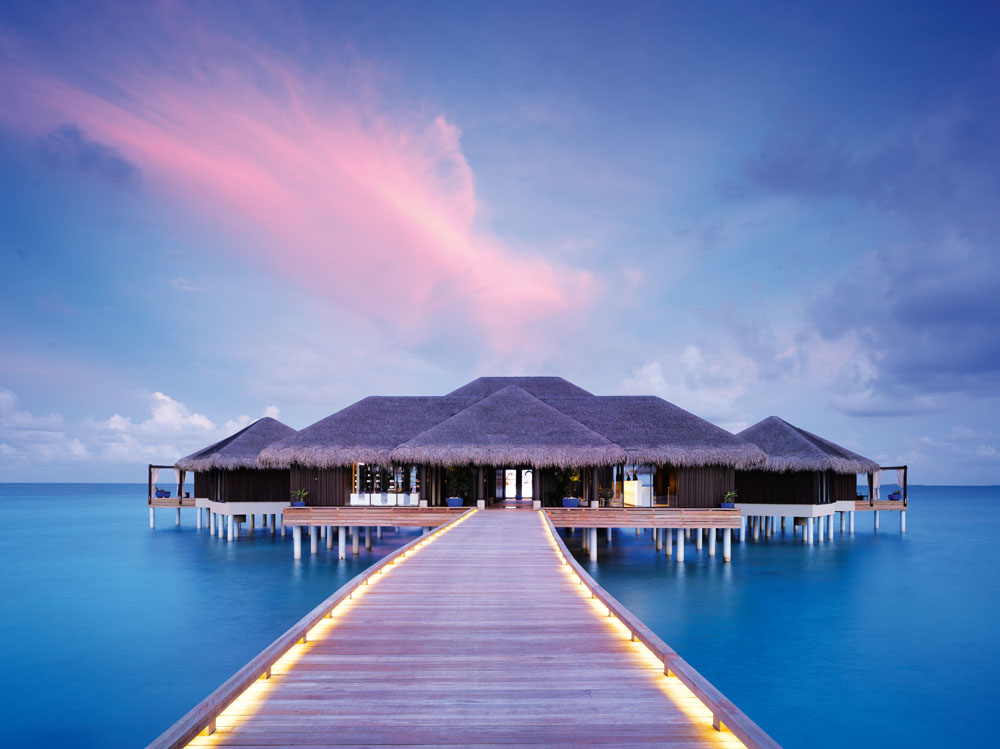 Luxurious overwater spa retreat with sunset skies and serene ocean views.