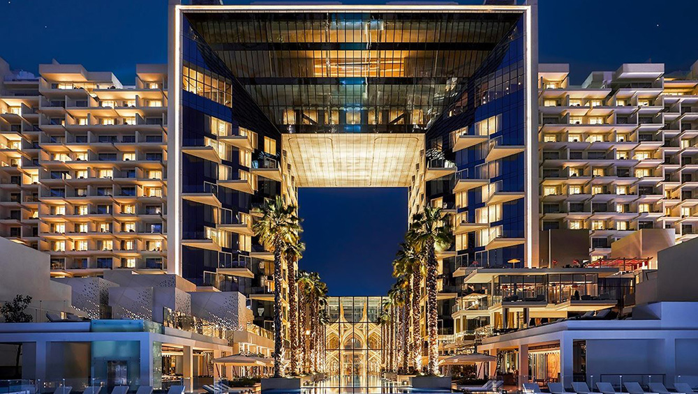 Luxurious modern spa resort entrance with elegant palm trees and ambient lighting at night.