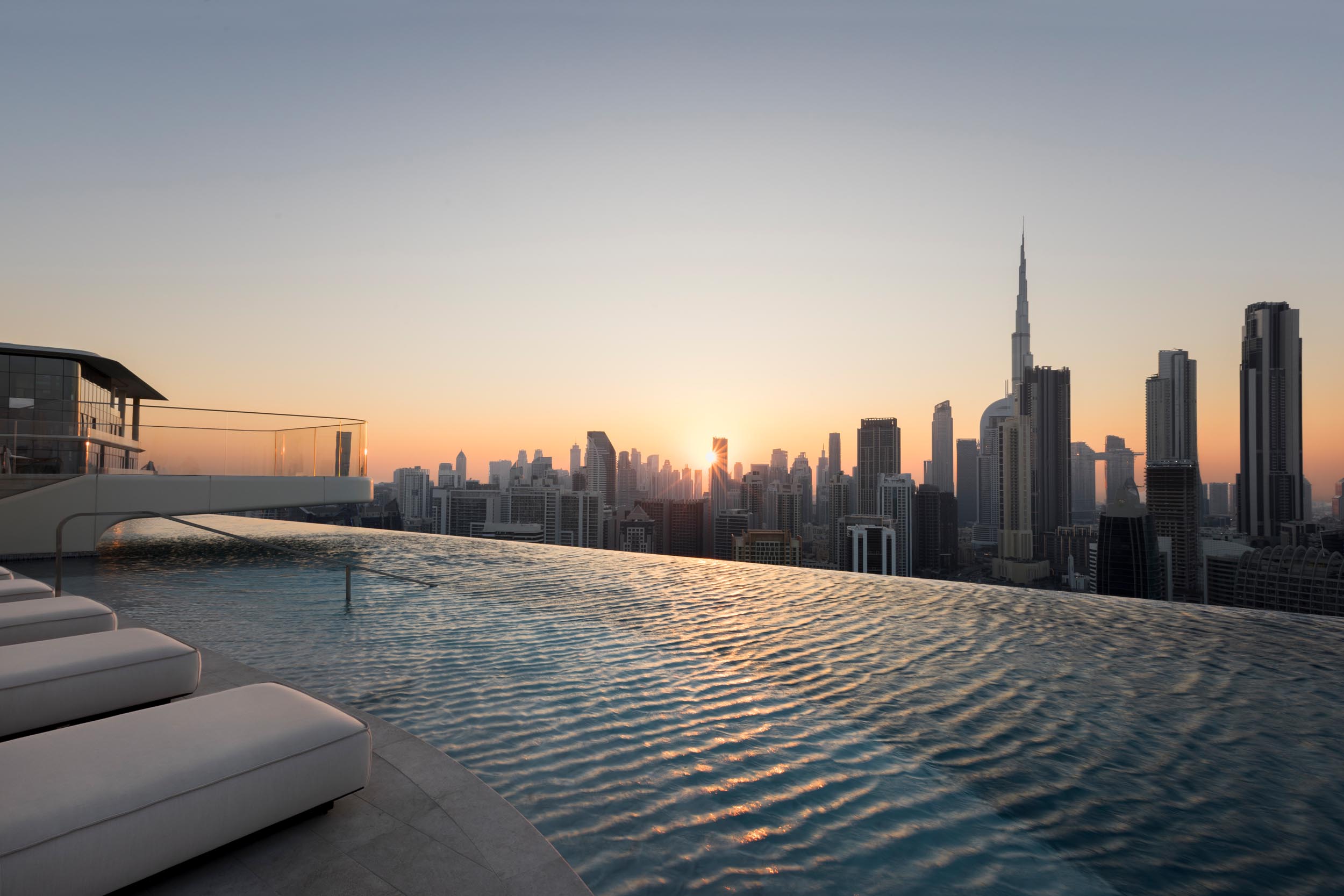 Luxurious rooftop infinity pool with city skyline at sunset, premium spa ambiance.