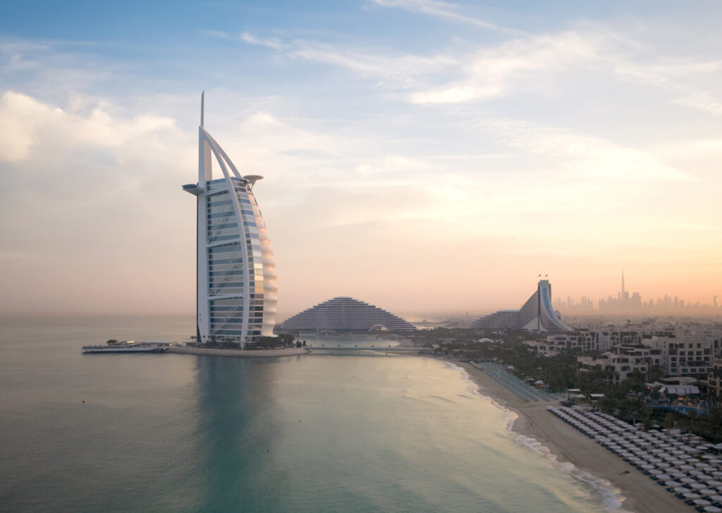 Skyline of Dubai with iconic luxury hotel by the sea at sunset.
